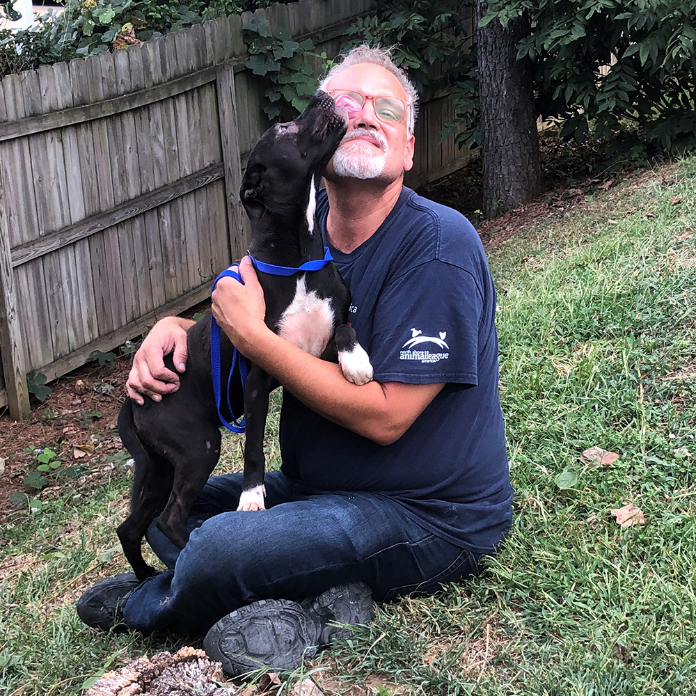 a man sitting on grass holding a dog