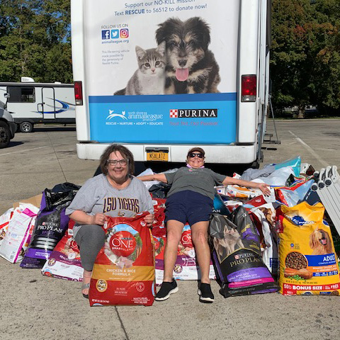 two women sitting on a pile of bags of food