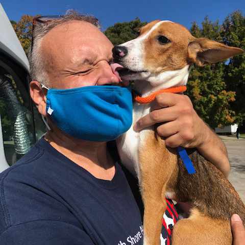 a man with a face mask licking a dog