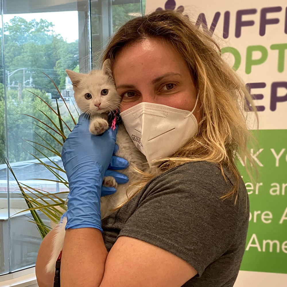 a woman wearing a mask and gloves holding a cat