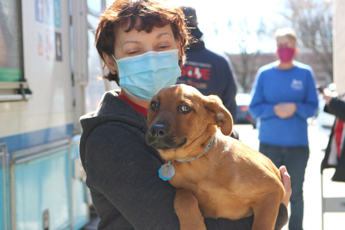 a woman wearing a face mask holding a dog