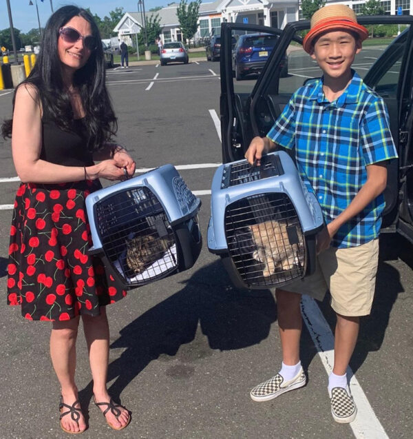a woman and boy holding pet carrier with cats in them