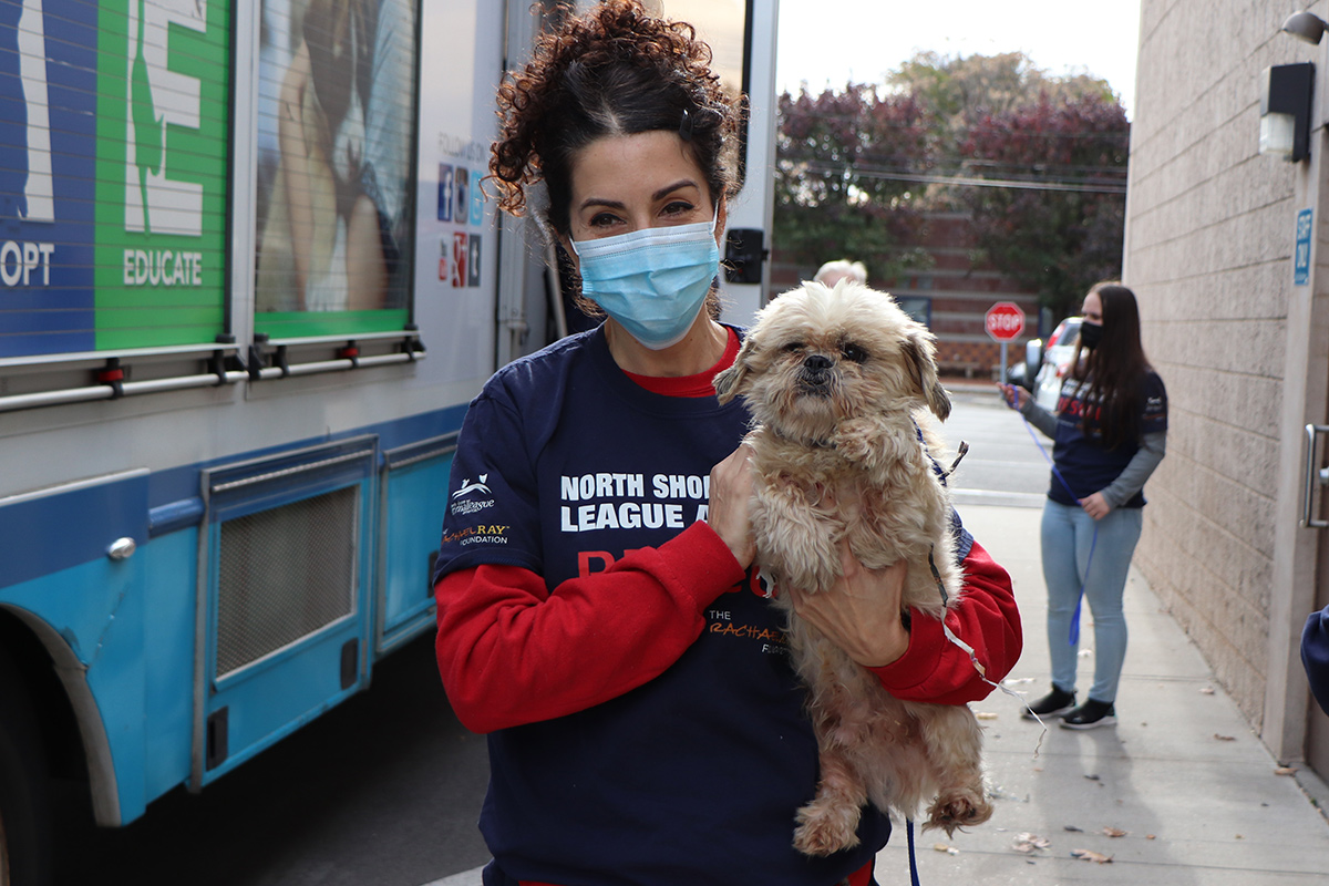 a woman wearing a face mask holding a dog