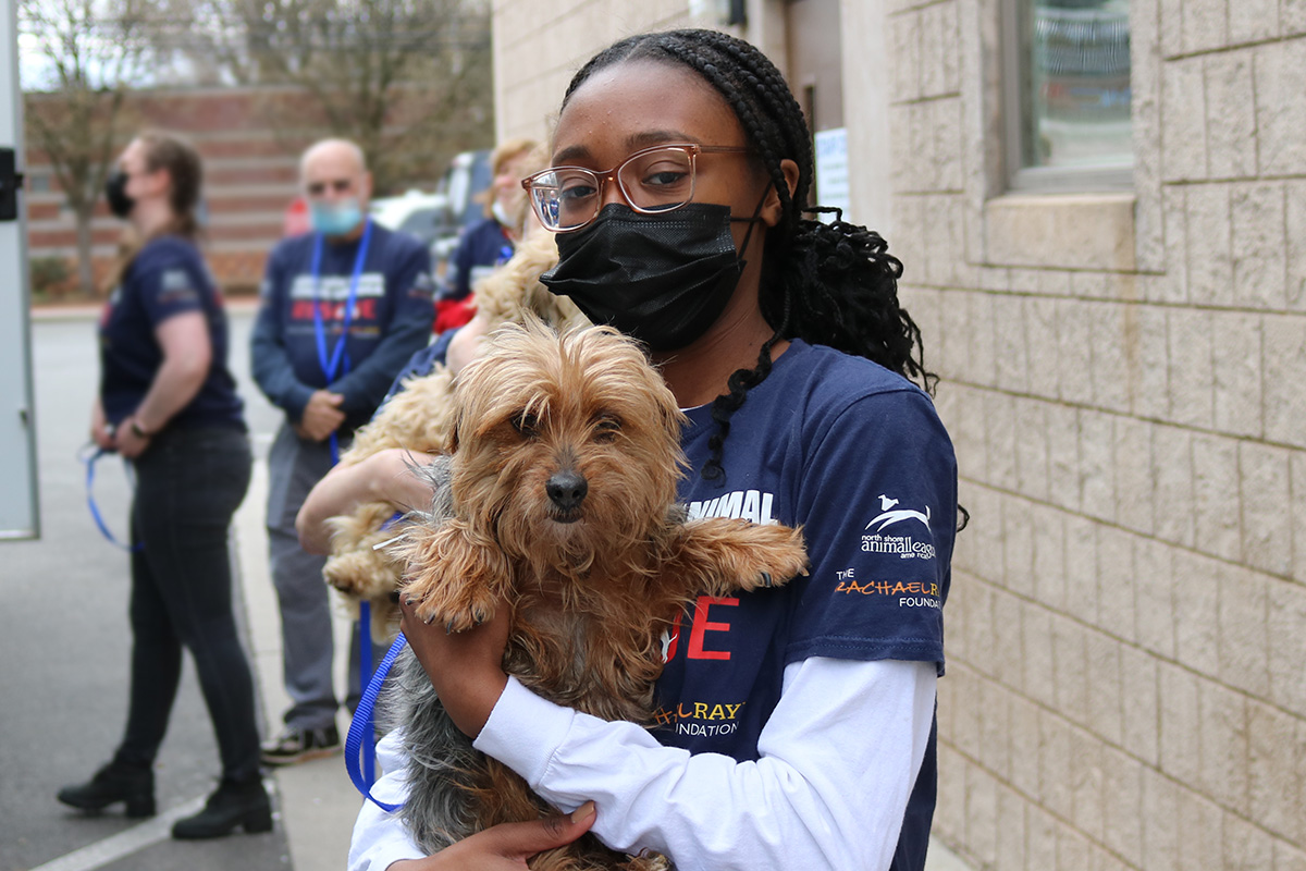 a woman wearing a face mask holding a dog