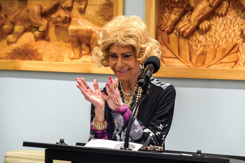 a woman in a wig speaking into a microphone