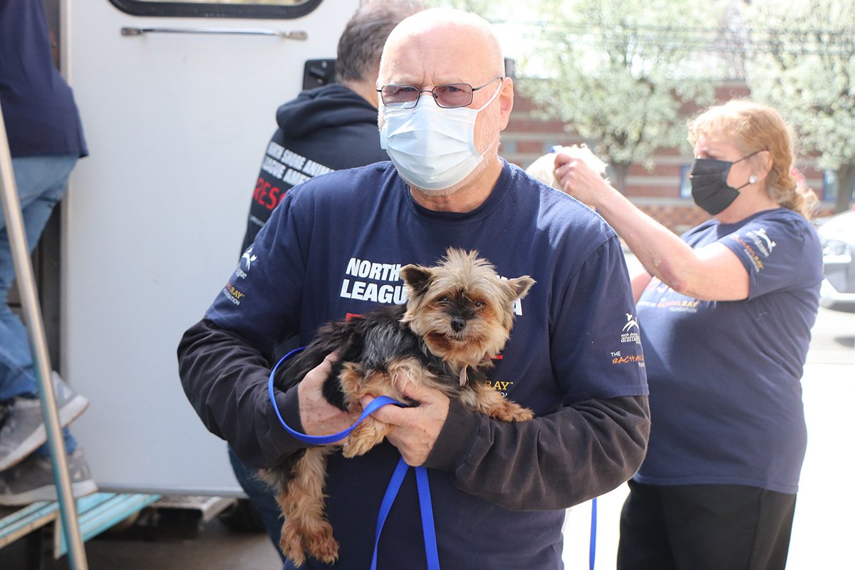a man wearing a face mask holding a dog