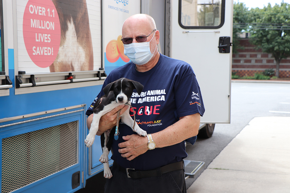 a man wearing a face mask holding a dog