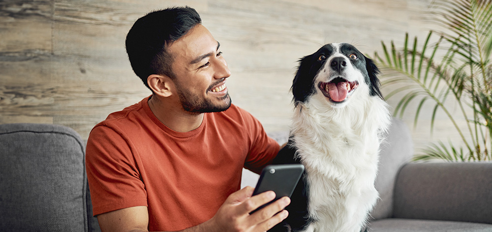 a man holding a phone next to a dog